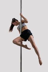 A young woman weared sports clothes in a pole dance movement. A dancer poses in a stretching...