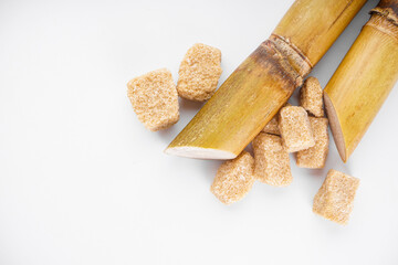 Sugar cane and brown sugar on a white background, space for text. Top view.