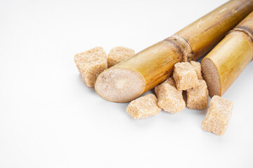 Sugar cane and brown sugar on a white background, space for text. Closeup.