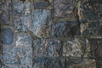 ancient wet stone-cladded textured wall background..