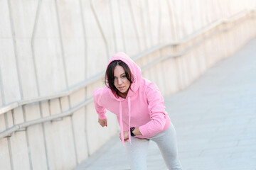 Portrait of fit and sporty young woman doing stretching in city.