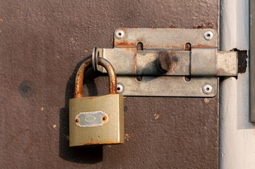 Old Metal Brown Door With A Handle And A Padlock. Red Rust Spots On Brown Paint.