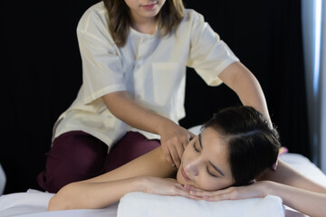 Obraz na płótnie Canvas Masseur doing massage on shoulder and body of young Asian woman in beauty spa salon.