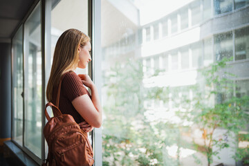 Shot of student girl looking through the window while she is observing and thinking