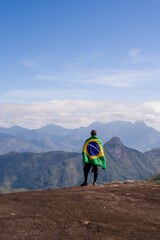 Obraz premium Young Man at Mountain Looking to Horizon in Nature with brazilian Flag.