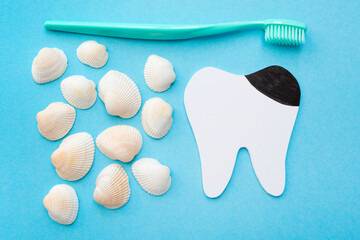 Tooth model with caries, toothbrush and seashells. Blue background. Flat lay. Top view. Benefits of...