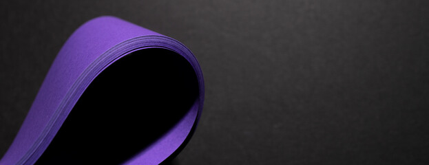 warping purple paper on purple surface on black