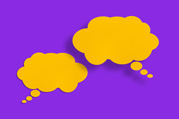 Speech balloon shaped yellow paper cloud against purple background.