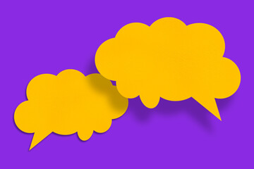 Speech balloon shaped yellow paper cloud against purple background.