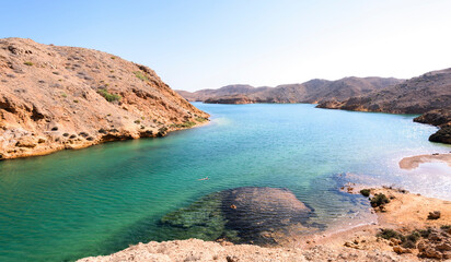 Woman swimming alone in a fjord-like in Sultanate of Oman, Middle East, Arabian Peninsula 