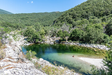 Fototapeta na wymiar Adult woman in a Pure and fresh water natural pool of Travu River, Corsica, France, Europe