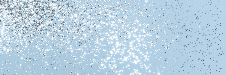 Sparkling silver glitter on blue background banner texture. Abstract holiday blurred lights header....