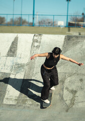 Cool young girl riding her skate on skate park concrete bowl.