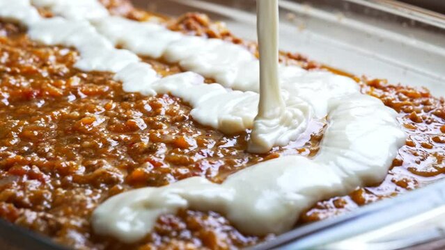Pouring bechamel sauce. Cooking lasagna.