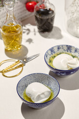 Aesthetic composition with  mozzarella cheese in olive oil. Fresh mozzarella cheese in ceramic bowl. Italian cuisine. Dairy cheese: mozzarella buffalo. Organic food in restaurant menu.