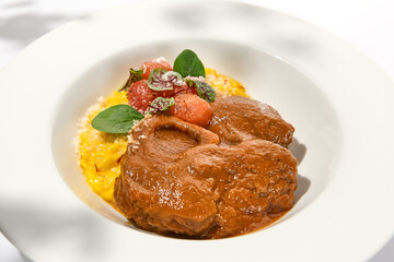 Traditional italian dish - osso buco with risotto milanese. Stew meat on bone with rice on white...