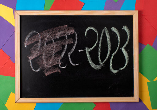 Pizarra con post its de colores en el fondo, escrito 2022 tachado y borrado, al lado 2023, año nuevo, nuevas metas y proyectos para el próximo año