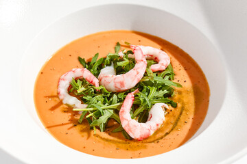 Summer Spanish soup gazpacho with shrimp and rocket salad isolated on white background. Healthy cold tomato soup with prawns. Clean eating for diet.Healthy food in restaurant menu. Seafood gazpacho