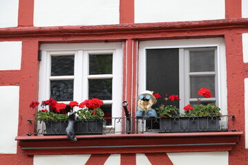 Fototapeta na wymiar window of a german half timbered house decorated with red flowers and funny statues