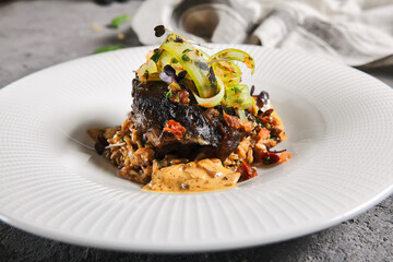 Braised beef cheeks with pearl barley and celery in creamy mushroom sauce. Veal cheek with mushroom risotto on gray stone background. Main course concept. Food menu for restaurant. - obrazy, fototapety, plakaty