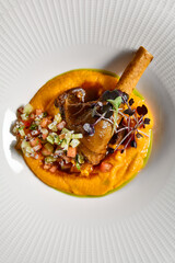 Slow roast leg of lamb with pumpkin puree and vegetables salsa. Roasted lamb with vegetables on gray stone table. Composition with meat dish on stone background. Meat menu ideas.
