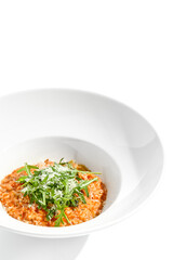 Vegan tomato risotto with ruccola on white plate. Italian dish - veggie risotto isolated on white...