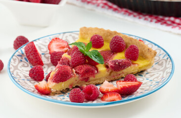 Round quiche with red strawberries and raspberries on a white table