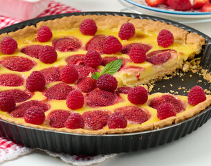 Round quiche with red strawberries and raspberries on a white table