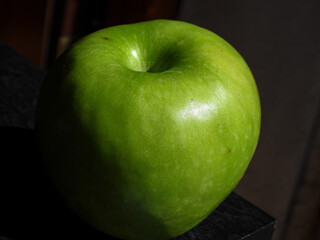 Manzana verde brillante sobre un fondo oscuro