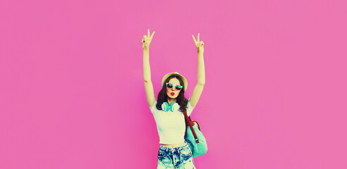 Obraz na płótnie Canvas Summer colorful portrait of stylish modern young woman having fun listening to music in headphones posing on pink background, blank copy space for advertising text