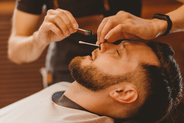 Removes hair from nose of man with wax master barber, depilation beauty procedure
