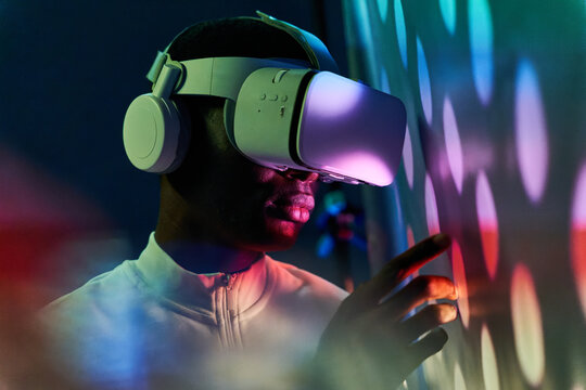 Serious black man touching large screen while exploring virtual reality in modern headset