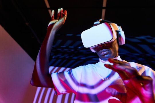 Black man looking at imaginary object while exploring cyberspace in VR glasses