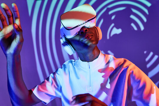 Black man looking at imaginary object while exploring cyberspace in VR glasses