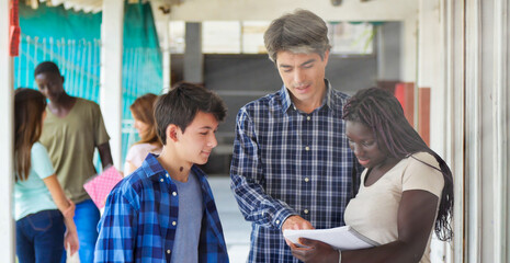 Obraz premium Teacher in the school hallway talking to his multi ethnic classroom