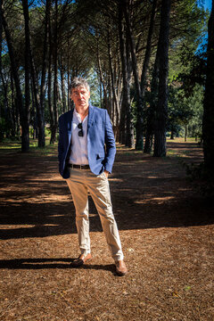 Beautiful blue-eyed man is wearing a blue jacket and bedge pants. Businessman is working outdoors in the park.