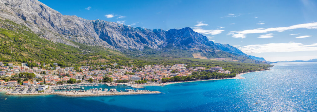 Panorama of Baska Voda town with harbor against mountains in Makarska riviera, Dalmatia, Croatia