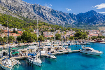 Fototapeta na wymiar Baska Voda town with harbor against mountains in Makarska riviera, Dalmatia, Croatia