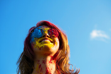 Woman covered in holi powder against blue sky. Holi colours festival.