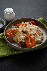 Close up of Risotto with mussels and shrimps cheese in bowl italian food on black surface