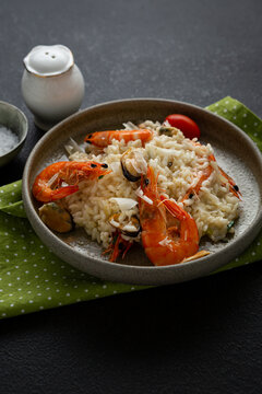 Close up of Risotto with mussels and shrimps cheese in bowl italian food on black surface