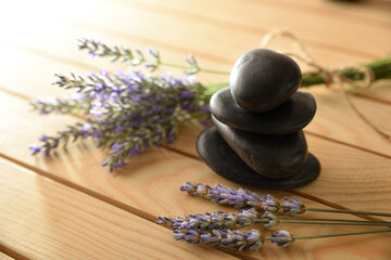 Obraz na płótnie Canvas Pile of black stones and lavender on wood table
