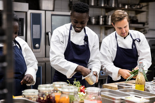 Chefs talking while preparing food in restaurant kitchen