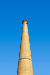 High minaret of the Muslim mosque against the blue sky