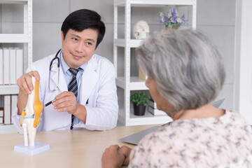 Fototapeta premium Male doctor explaining anatomical feet with elderly patient asian woman in hospital