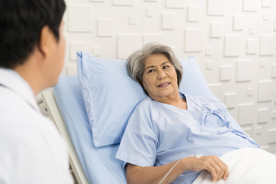 Male doctor visit elderly patient asian woman on bed at the hospital. People and health care concept