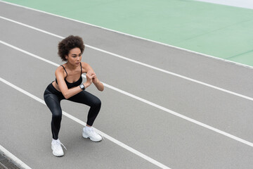 athletic african american woman in white sneakers doing sit ups with clenched hands.