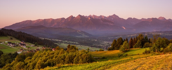 Wide panorama of Tatra Mountains in Podhale region of Poland at summer sunrise