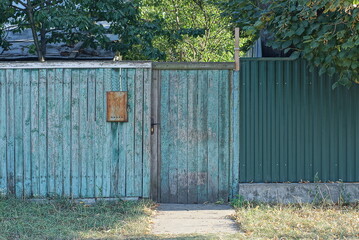 Fototapeta na wymiar one closed gray green wooden door on a rustic fence wall in the street