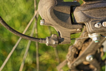 part of a black iron bicycle brake with a cable on a bicycle wheel on a green background